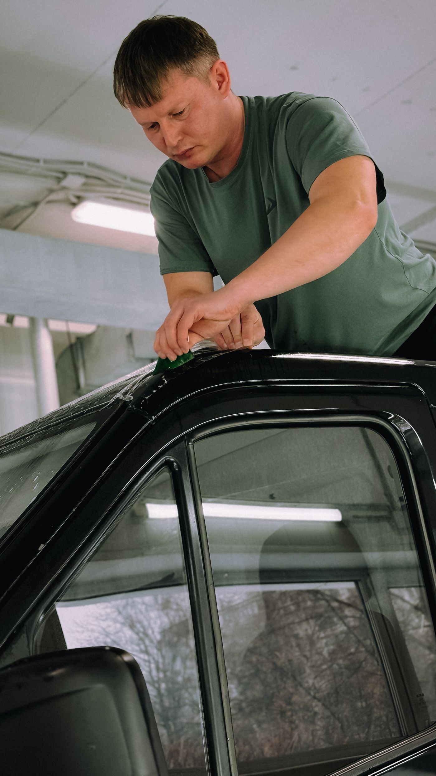 Installer applying tint film to a car's front door window